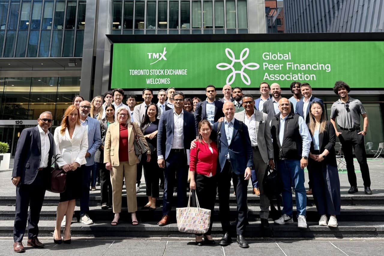 Members of the Global Peer Financing Association gathered on the steps of the Toronto Stock Exchange, whose marquee welcomes the association.